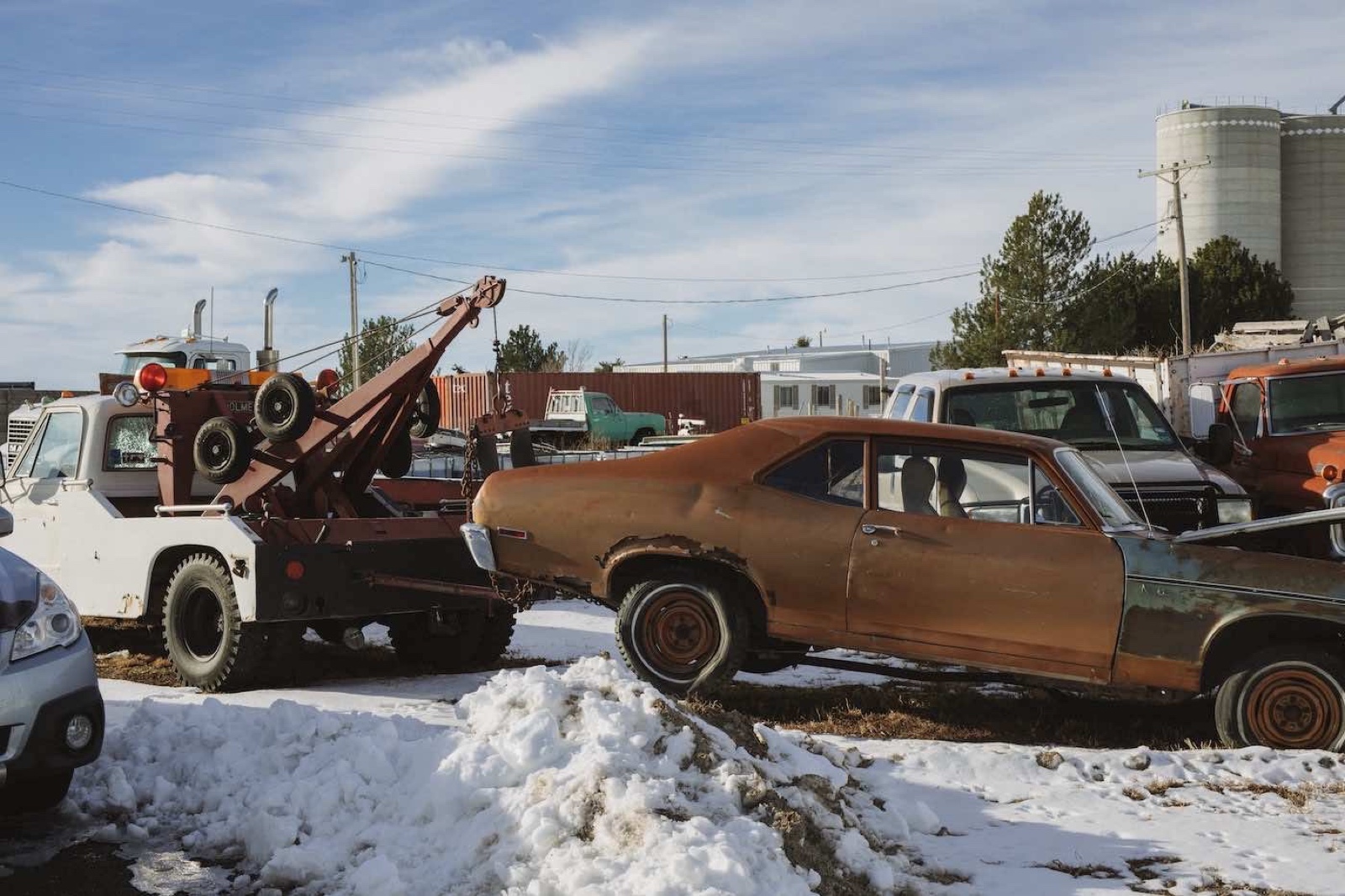 Old tow truck and junk car inside an auto recycling yard